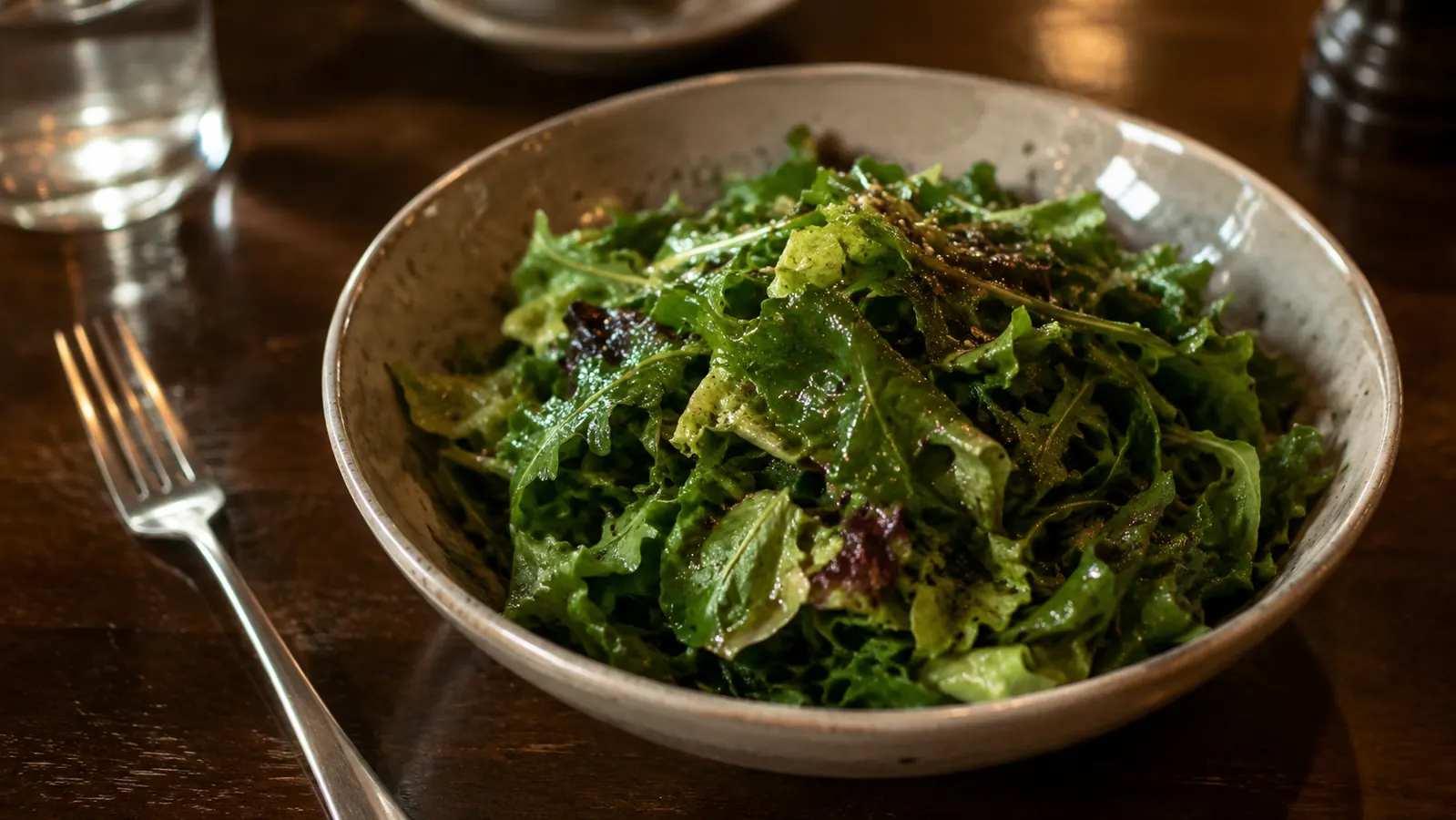 A crisp green salad tossed with dressing in a wooden bowl on a dinner table