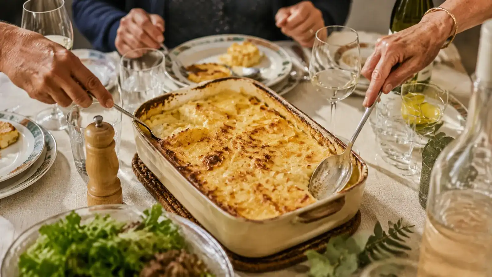 A finished golden potato gratin on a dinner table surrounded by family at a Sunday gathering